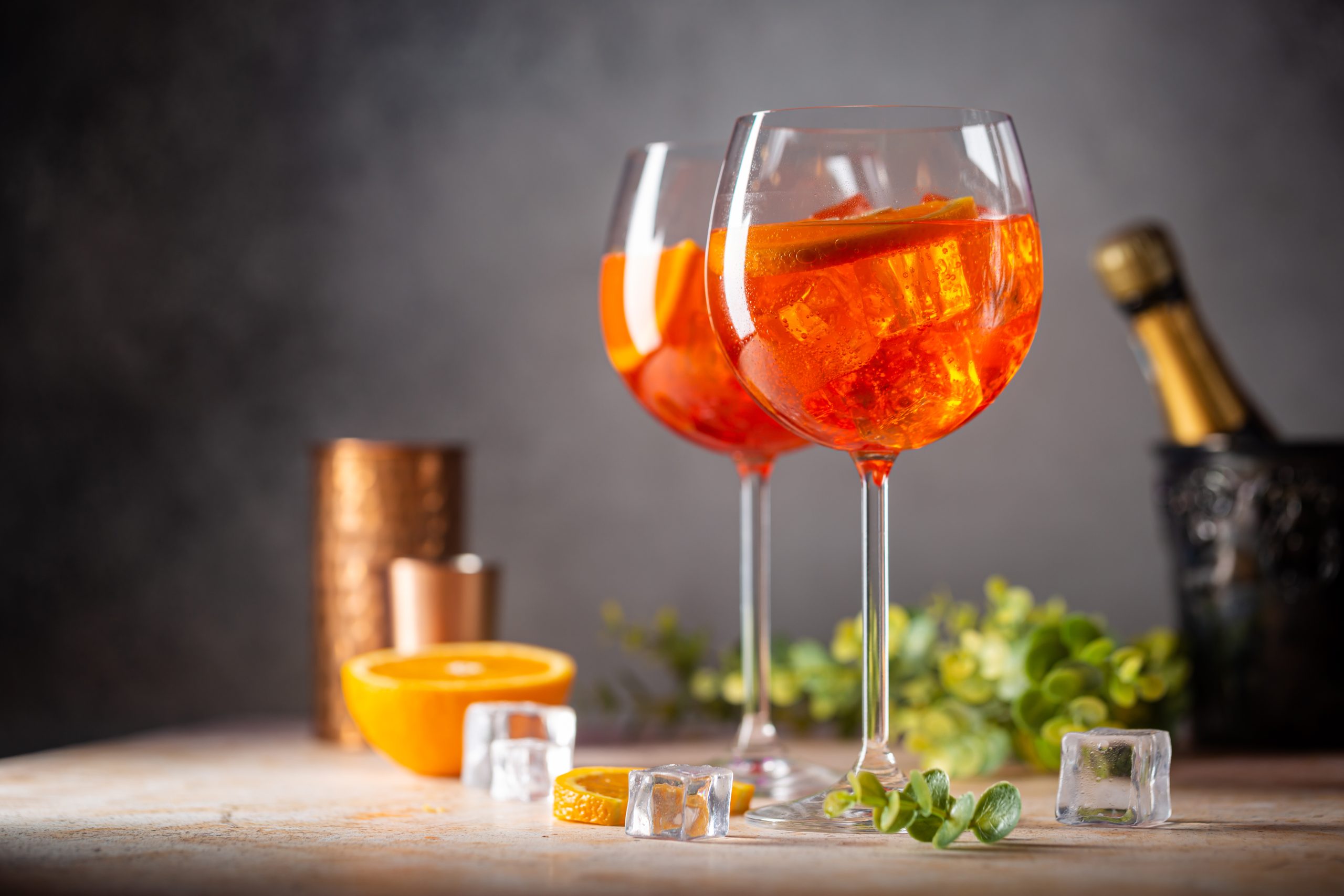 Aperol spritz cocktail in glass with fresh orange on gray background